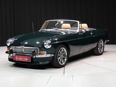 a green convertible car parked in front of a black wall