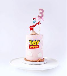 a toy story birthday cake on a white plate with a pink frosting topper