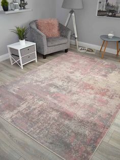 a living room with a gray couch and pink rug on the floor next to a chair