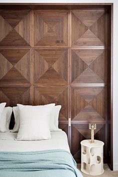 a bed with white pillows and wooden paneling on the headboard in a bedroom