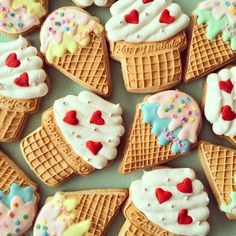 ice cream and heart shaped cookies are arranged on a table with frosting, sprinkles, and hearts