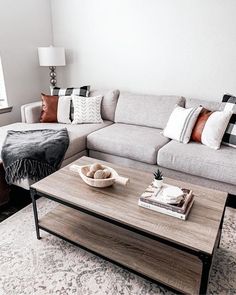 a living room filled with furniture and pillows on top of a rug in front of a window