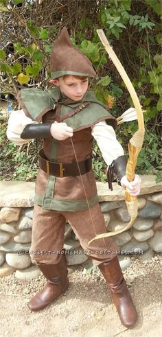 a young boy dressed in costume holding a bow and arrow