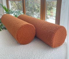 two orange pillows sitting on top of a bed