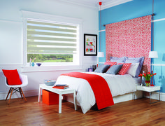 a bedroom with blue and red walls, white bedding, and orange accents on the headboard