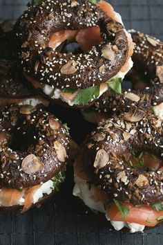 several bagels with various toppings are arranged on a cooling rack, ready to be eaten