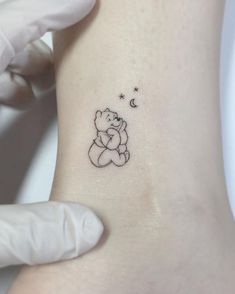 a small teddy bear tattoo on the left side of the right arm, with stars and moon above it