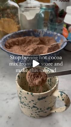 a spoon in a cup filled with cocoa on top of a counter next to other bowls