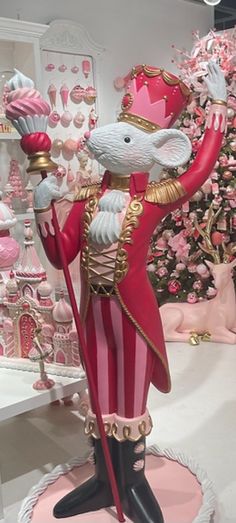 a statue of a mouse dressed as a nutcracker holding a pink lollipop