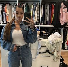 a woman standing in front of a closet holding her hand up to the camera and making a peace sign