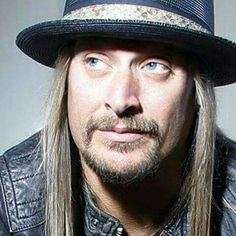 an image of a man with long hair wearing a hat and looking at the camera