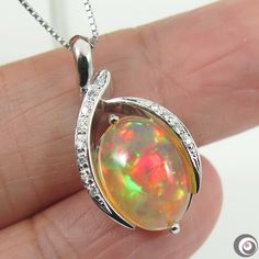 "Fine hand-crafted solid platinum (Pt.900) pendant with 0.07ctw. of sparkling natural mined accent diamonds and a large 3.676ct. of  Ethiopian flashy 'harlequin\", untreated \"fire opal\". So striking rolling flashed of rainbow colors (red, green, blue, orange gold; etc.). The necklace is also made of platinum (stamped: Pt850).  It is fine, dainty necklace, which about 0.7mm in thickness & 17.5 inches in length and can be adjust to shorten it. Style: Pendant Necklace Precious Metal: Solid Platinum (PT900) Genuine diamond: 0.07ctw. Pendant Size (L x W):  13.5mm x 25.8mm Necklace Length: 17.5 inches & adjustable. Total Weight (includes chain): 8.7 grams. Opal Type: Welo Opal. Size: 9.5 x 13.8mm Weight: 3.676ct. Color:   Beautiful array of color spectrum. Treatment: Natural (untreated). Origi Oval Diamond Necklace With Polished Finish For Gifts, Silver Oval Diamond Necklace With Gemstone, Oval Silver Gemstone Diamond Necklace, Platinum Oval Necklace As Gift, Platinum Oval Necklace For Gifting, Platinum Oval Necklace For Gift, Oval Silver Diamond Necklace With Gemstone, Platinum Oval Necklaces For Gifts, Silver Diamond Jewelry With Bail