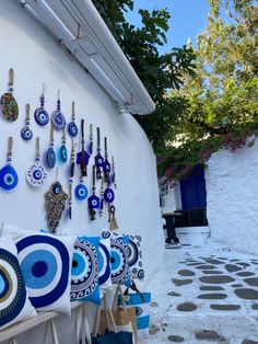 many earrings are hanging on the wall next to each other in front of a white building