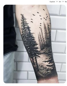 a man's arm with trees and birds in the sky on his left forearm