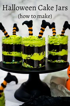 halloween cake jars with candy in them on a black tray and decorated with green icing