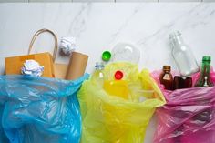 three plastic bags are lined up against a marble wall with bottles and other items in them