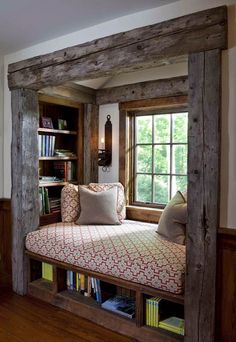 a window seat in the corner of a room with bookshelves and pillows on it