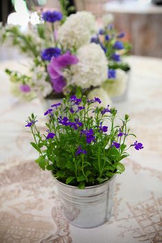 some purple and white flowers are in a tin can