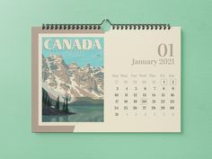 a calendar with the image of a mountain range in canada is hanging on a green wall