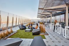 people are sitting outside on the roof of a building with grass in front of them