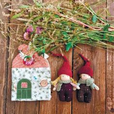 two little gnomes sitting next to each other in front of a small house with flowers