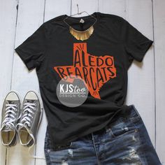 "Aledo Bearcats Tee - Aledo TShirt - Bearcats Shirt - Orange and Black Aledo Tee - Aledo Football Tee - Custom Highschool Tee - School Tee {$25} Before completing your purchase, please refer to our \"Shop Announcement\" and \"Shop Policies\" sections for important information, FAQ's, current turnaround times and upcoming closing dates. SIZING AND COLOR INFORMATION -We use UNISEX sizing for all our shirts, which means they run longer and looser than your typical women's tee. -If you prefer a more Black T-shirt With Screen Print For School, Black Screen Print T-shirt For School, Black Relaxed Fit T-shirt With School Spirit, Casual Fitted T-shirt With Team Name, Black Relaxed Fit Top For School Spirit, Black T-shirt With Sublimation Print For School Spirit, Black T-shirt With Sublimation Print For School, Black Casual T-shirt For School, Black Relaxed Fit Tops For School