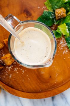 a wooden plate topped with food and a glass filled with liquid next to lettuce