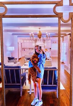 a woman taking a selfie in front of a mirror with a dog on her lap