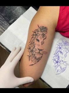 a woman's arm with a lion and flowers tattoo on the left side of her arm