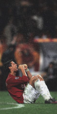 a soccer player sitting on the ground with his head in his hands and mouth wide open