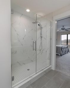 a bathroom with a walk in shower next to a large window and tiled flooring