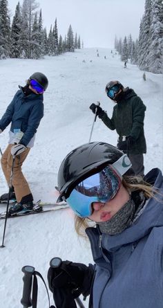 two people on skis in the snow with helmets and goggles over their eyes