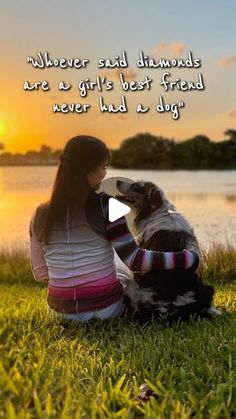 a woman sitting next to a dog on top of a grass covered field at sunset