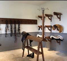 a wooden horse saddle stand in front of a wall filled with horses'tacks