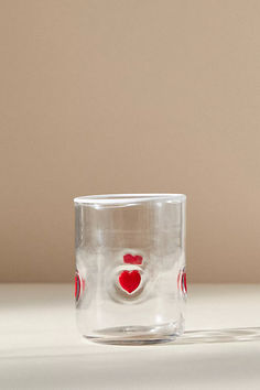 a clear glass with a red heart on the side and a white background behind it