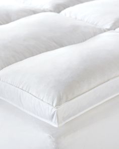 an unmade bed with white sheets and pillows on it's side, close up