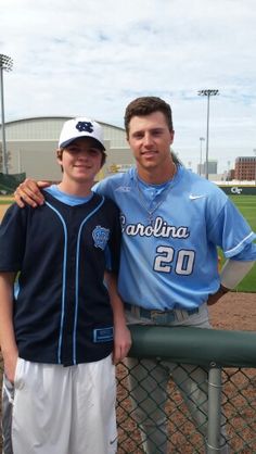 two baseball players standing next to each other in front of a fence on a field