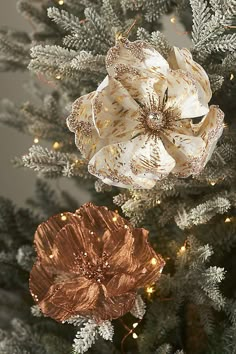 two ornaments are hanging from the top of a christmas tree in gold and white colors