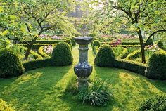 a garden with lots of green grass and trees in the center, surrounded by hedges