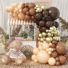 a teddy bear sitting in front of a bunch of balloons that are brown, gold and white