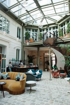 a living room filled with lots of furniture under a glass ceiling