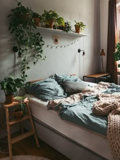 an unmade bed in a bedroom with plants on the wall