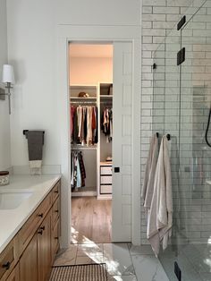 a walk in shower sitting next to a white sink and counter top under a mirror