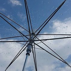 an open umbrella with rain drops on the glass and blue sky in the back ground