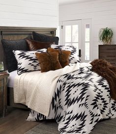 a bed with black and white comforter, pillows and blankets on top of it