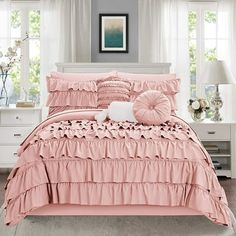 a pink bed with ruffled sheets and pillows