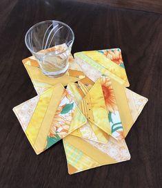 a table topped with yellow and orange place mats next to a glass filled with water