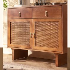 a wooden cabinet with two doors and some baskets on top of it next to a potted plant