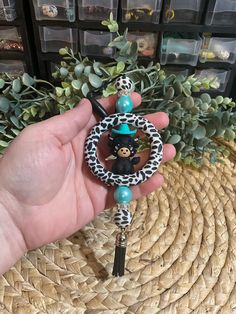 a person holding a keychain with a monkey on it's back and a leopard print bead around the neck