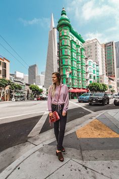 a woman standing on the sidewalk in front of some buildings